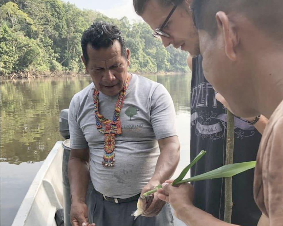 a tourist observes as two local guides prepare to fish for piranhas