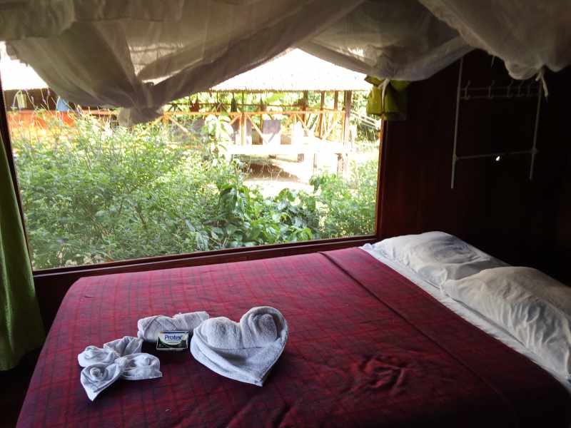 View over a Queen bed to the main lodge at Cuyabeno Kichwa Lodge