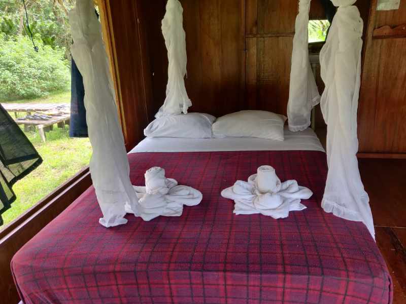 A Queen bed with views outdoors at the Cuyabeno Kichwa Lodge