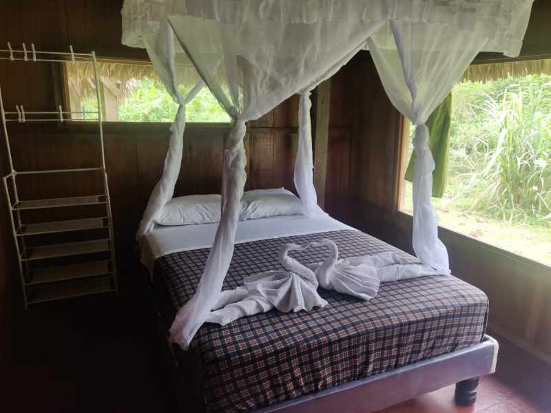 Queen bed with mosquito netting and towels folded in the shapes of swans at the Cuyabeno Kichwa Lodge.